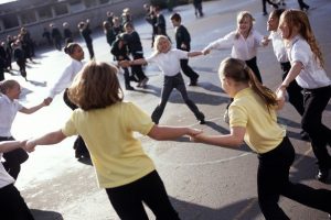 Children holding hands playing "Ring Around the Rosie"