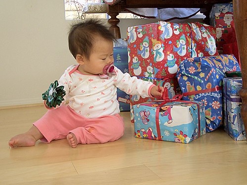 A baby next to Christmas presents