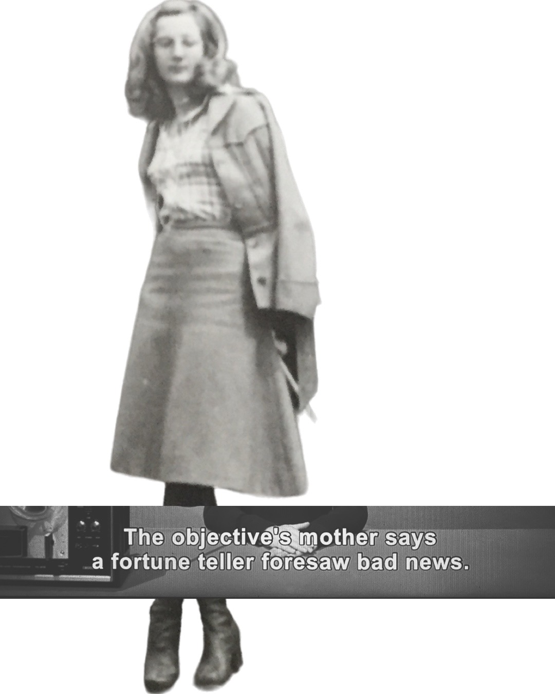 Black and white film still of the author's mother. She is wearing a dress with a plaid shirt and a jacket.