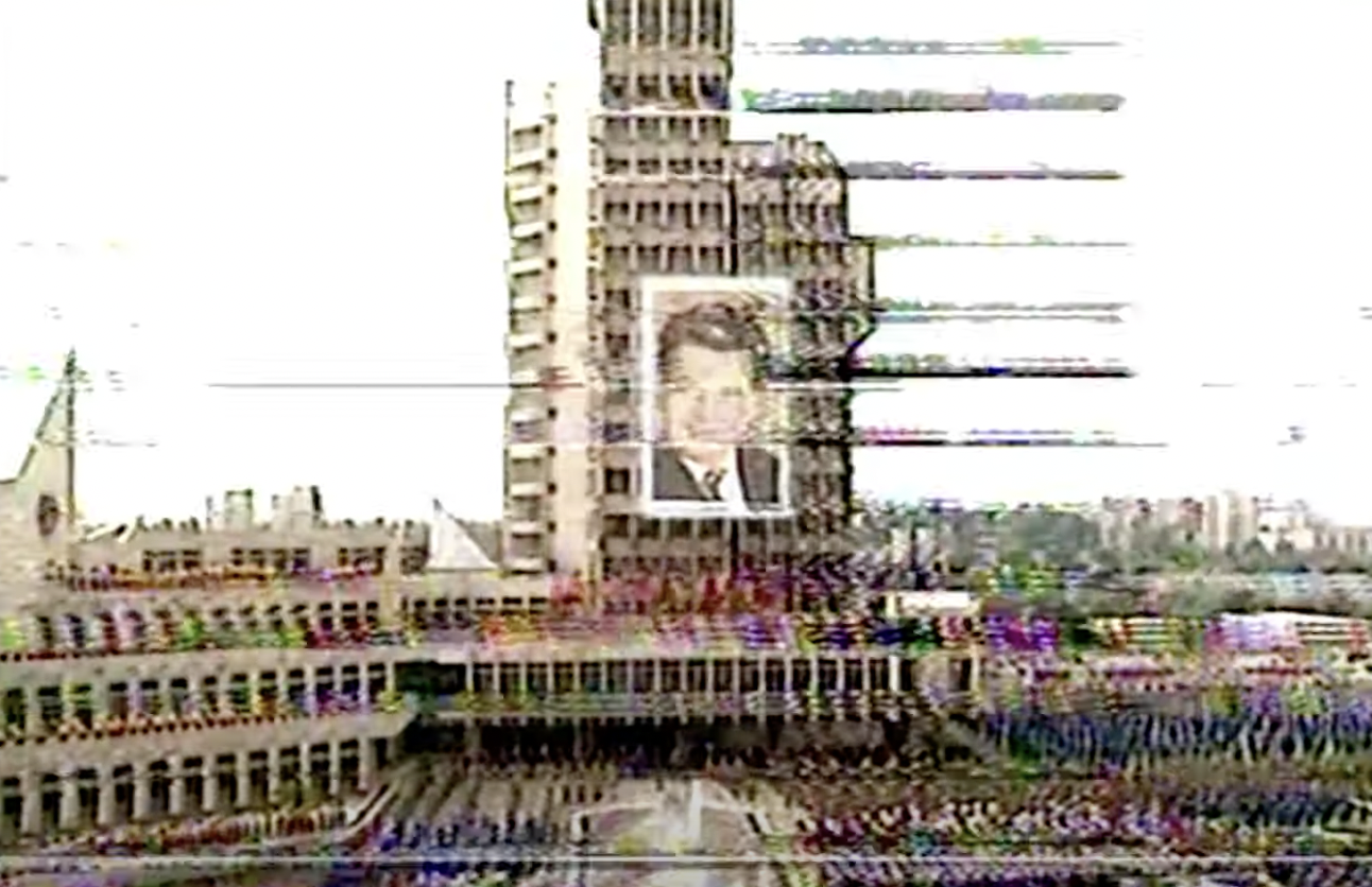 Blurry video still of a crowd at an event in honor of dictator Nicolae Ceaușescu.