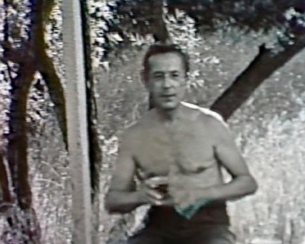 Black and white image of the author's grandfather, Gheorghe Gancevici. He is shirtless and sitting outside holding a drinking glass.