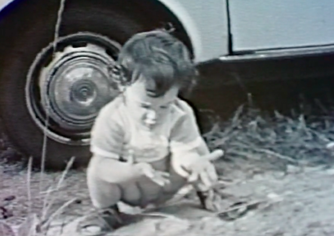 A black-and-white childhood photo of the author as she squats and stares at her outstretched hands.